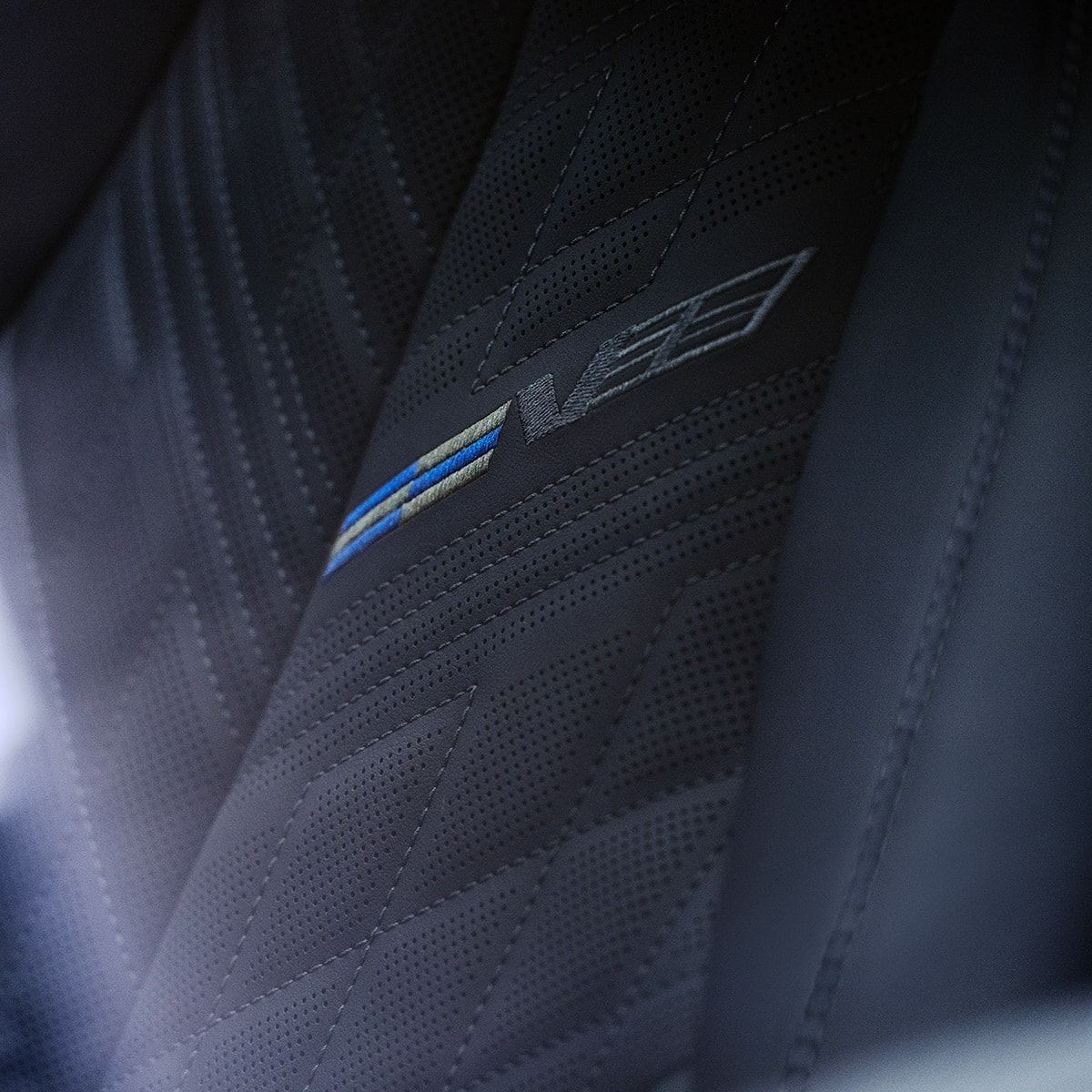 Close-up of V-Series embossed leather sport seat with blue stitching.