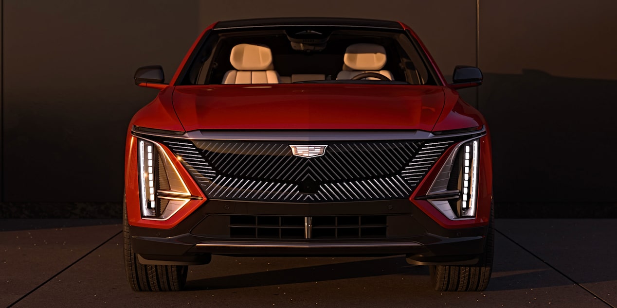 Front view of a red 2027 Cadillac LYRIQ showcasing its illuminated grille and vertical LED lighting signatures.