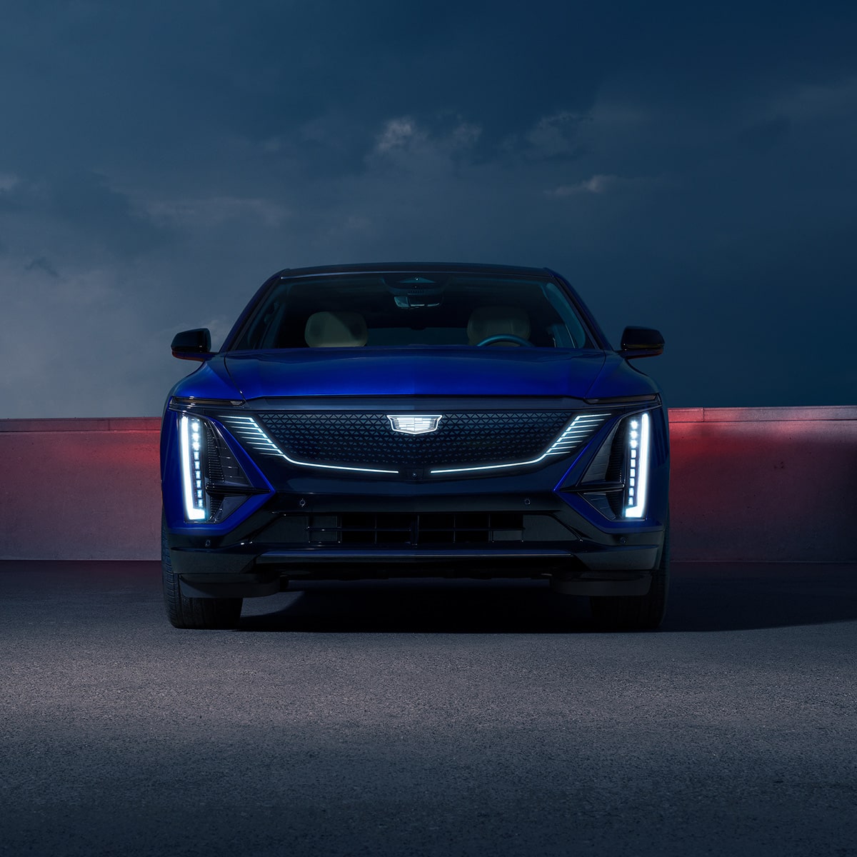 Front view of the 2027 Cadillac LYRIQ with its headlights lit up.