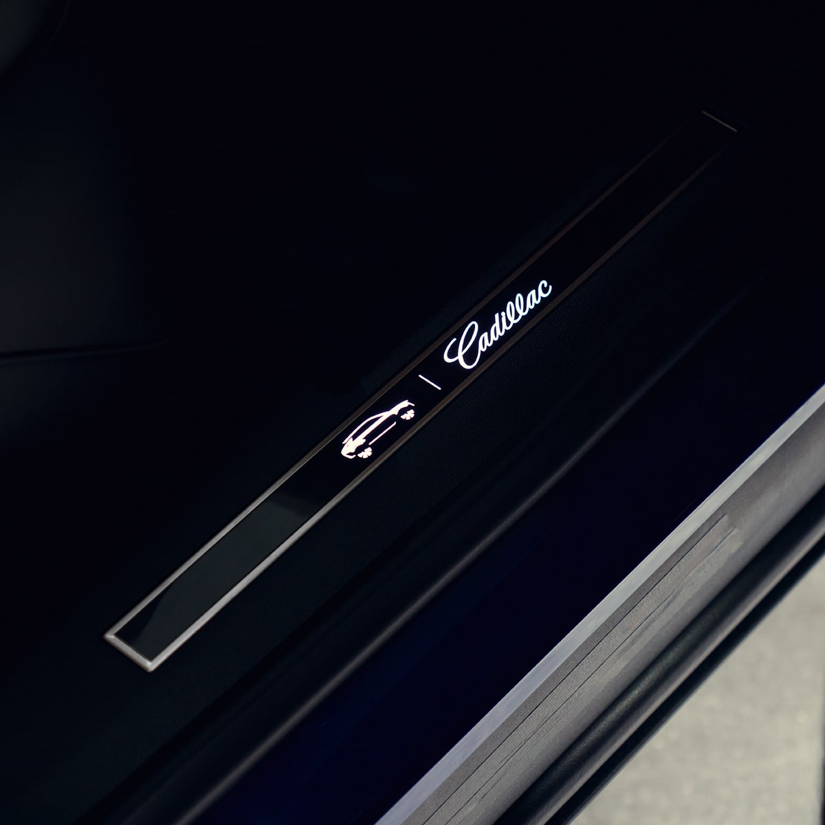 Close-up of the illuminated Cadillac-branded door sill plate inside the 2027 Cadillac LYRIQ.
