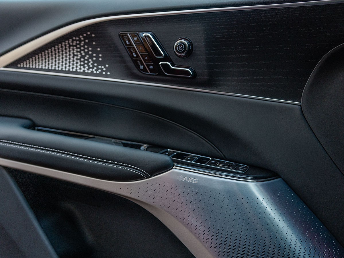 Close-up of the 2027 Cadillac LYRIQ-V interior door panel featuring a premium AKG audio system speaker.