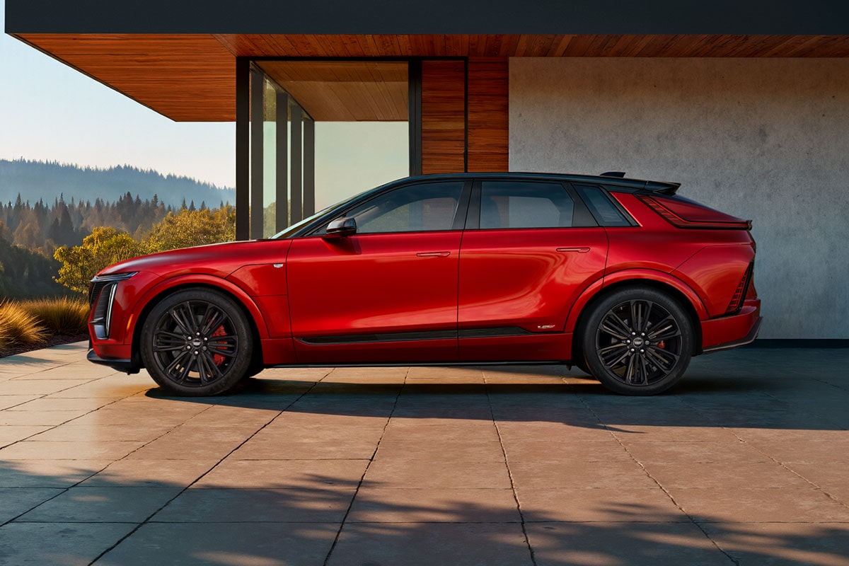 Side view of the 2027 Cadillac LYRIQ-V SUV parked outside a modern home.