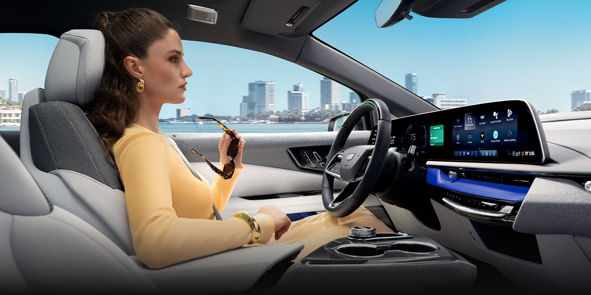 Passenger View of a Woman Driving a Cadillac OPTIQ Past the City While Utilizing Super Cruise Hands-free Technology