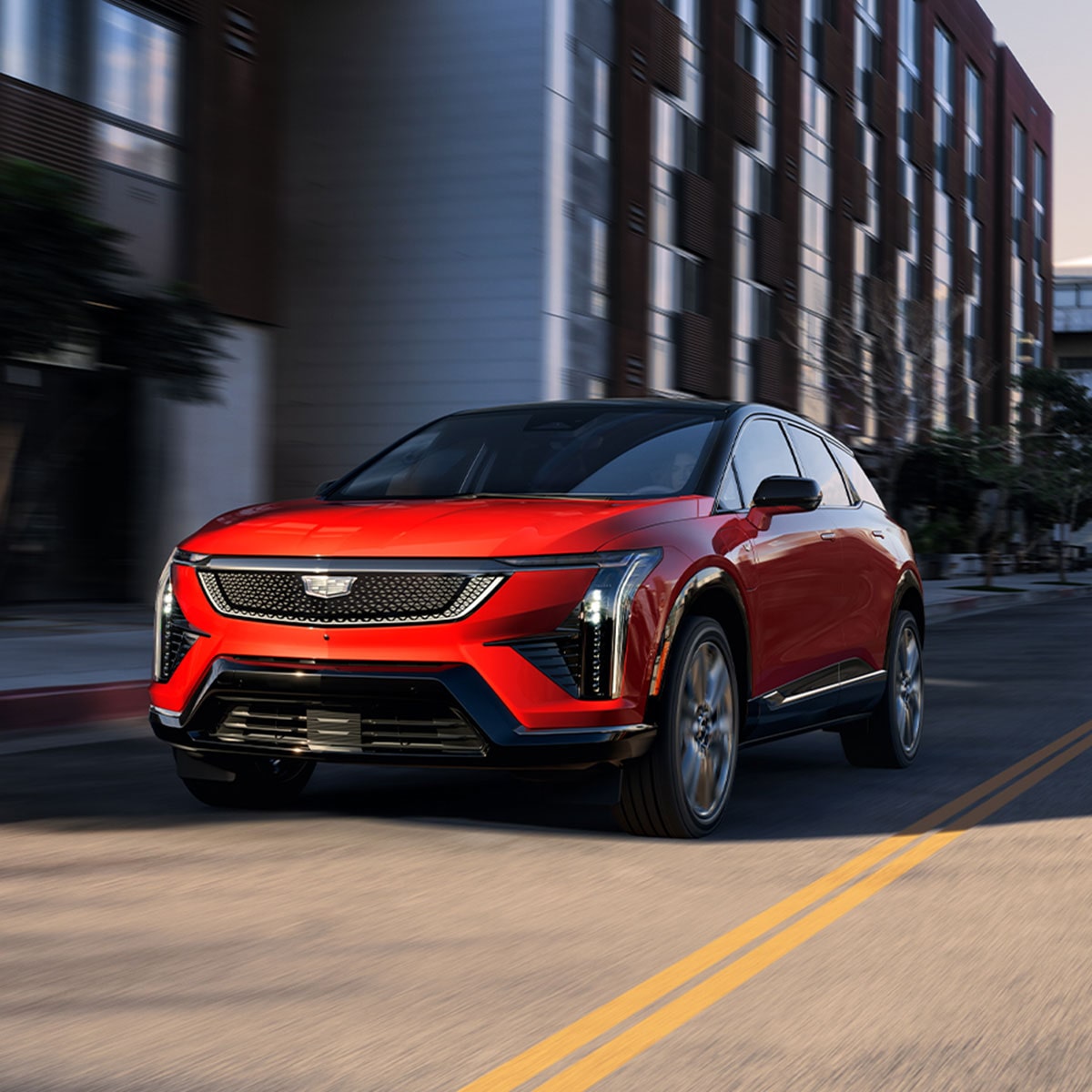 Le soleil qui brille sur une Cadillac OPTIQ rouge 2027 en conduisant en ville.