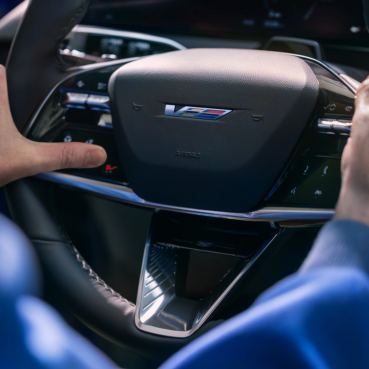 Gros plan de quelqu’un appuyant sur le bouton V sur un volant Cadillac OPTIQ-V.