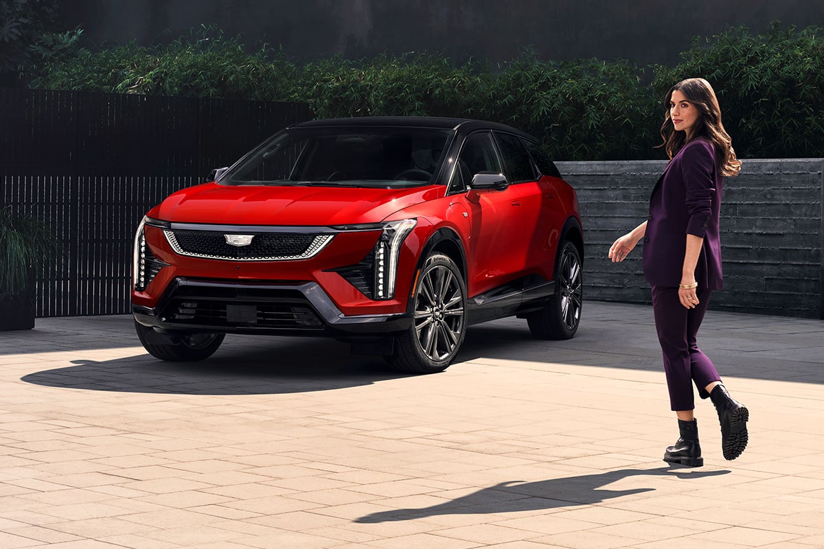 Une personne marchant vers une Cadillac OPTIQ rouge 2027 stationnée.