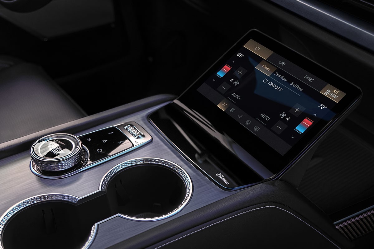 Close-up of the 2027 Cadillac VISTIQ Middle Console Including the Cup Holders, Gear Knob and Climate Control Screen.