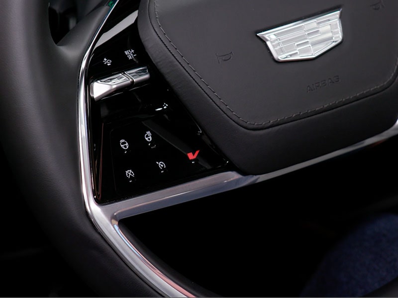 Close-up of the V Button on the 2027 Cadillac VISTIQ Steering Wheel.