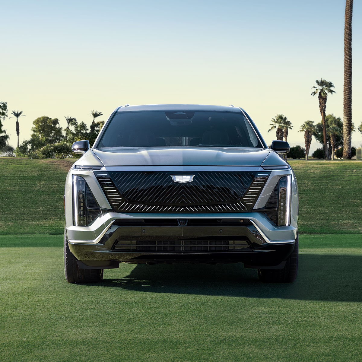 Vue de face d’un VISTIQ 3 rangées de SUV électrique 2027 garé sur un court de tennis herbeux.