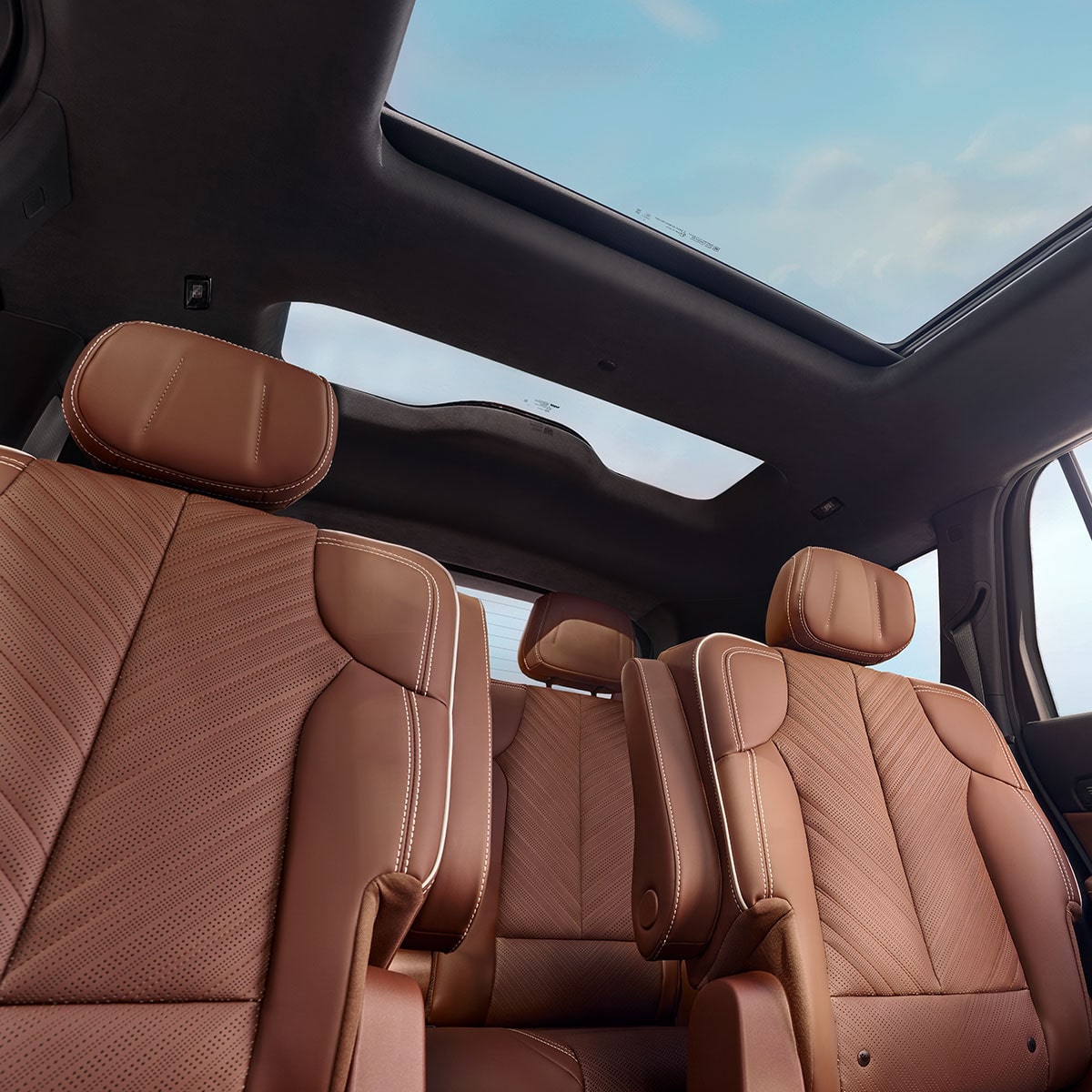Vue intérieure des deux rangées arrière en cuir marron de la Cadillac VISTIQ 2027 et son toit ouvrant à double vitrage.