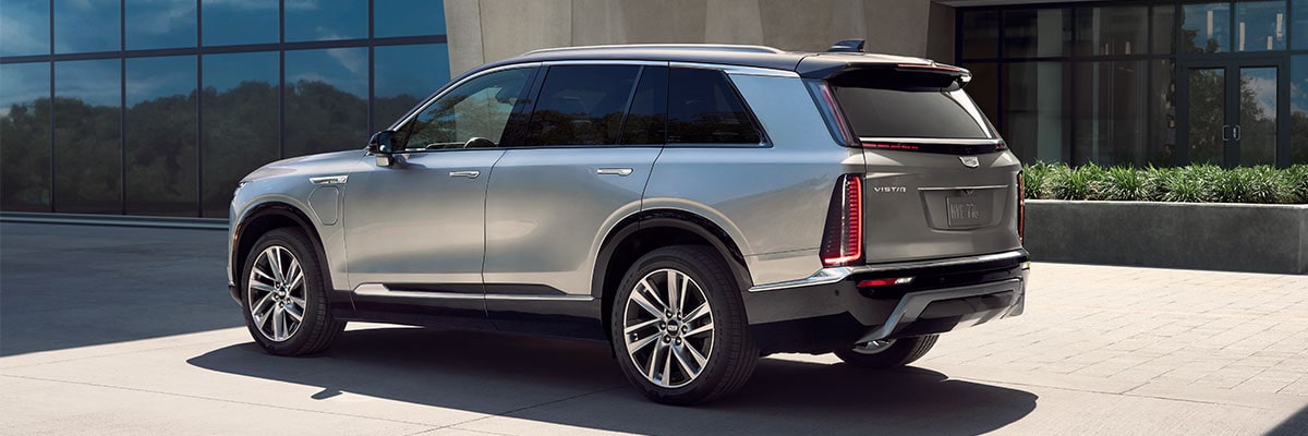 Three-quarters Rear View of the 2027 Cadillac VISTIQ Parked Outside of a Modern Building.