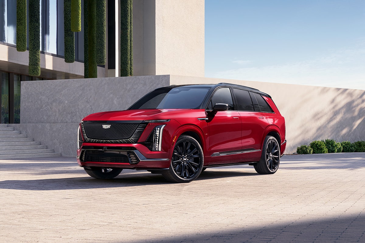 Three-quarters View of a 2027 VISTIQ 3-row Electric SUV Parked near a Concrete Wall.