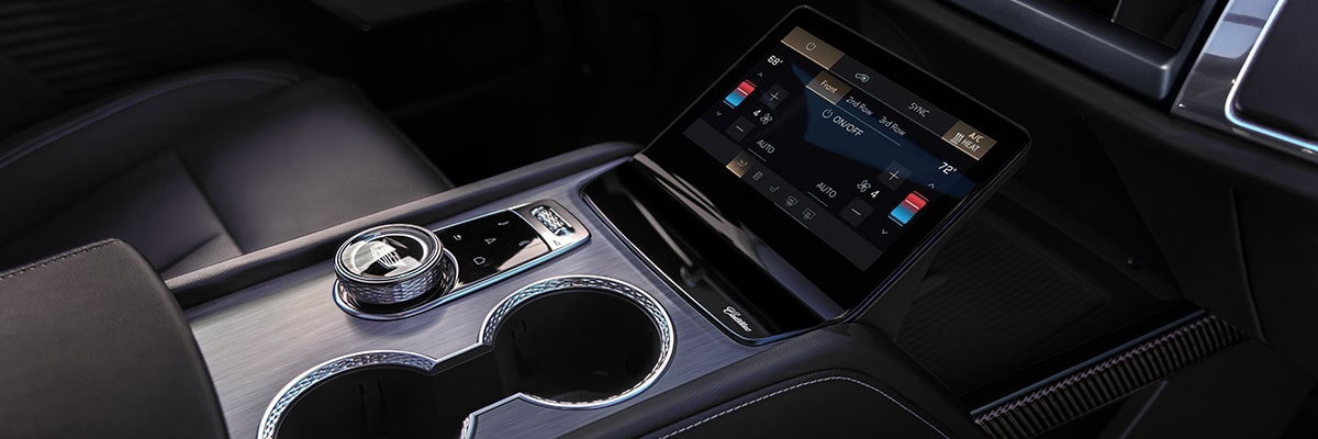Close-up of the 2027 Cadillac VISTIQ Middle Console Including the Cup Holders, Gear Knob and Climate Control Screen.