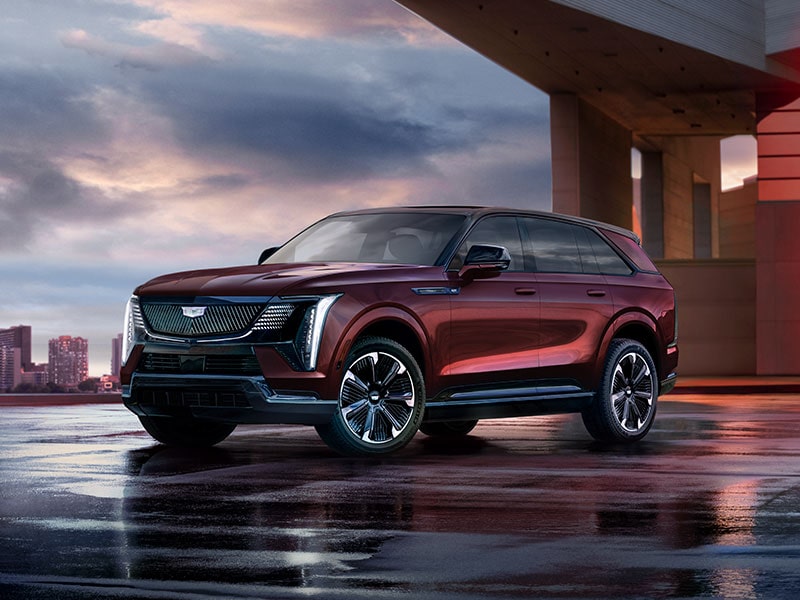 2026 Cadillac Escalade IQ electric suv parked outside a brightly-lit modern home.