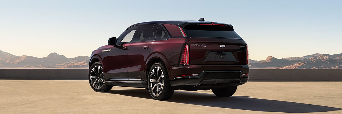 Rear three-quarter view of a Cadillac Escalade IQ electric SUV parked alone in an arid region.