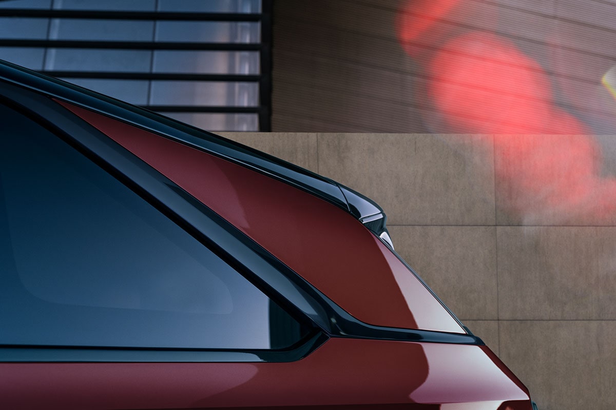 Close-up view of the rear corner of a Cadillac Escalade IQ electric SUV parked against a modern building backdrop.