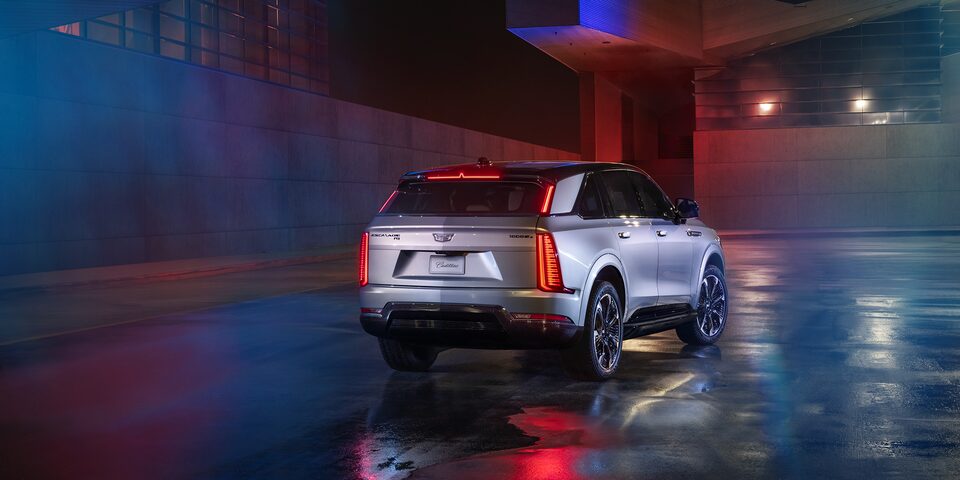 Rear profile view of the 2024 Escalade driving on the road.