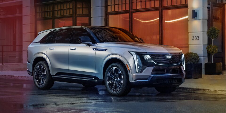Front right profile view of the 2024 Cadillac Escalade IQ parked outside a road.