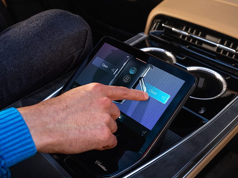 Une personne assise à la deuxième rangée du Cadillac Escalade IQ utilise un écran tactile.