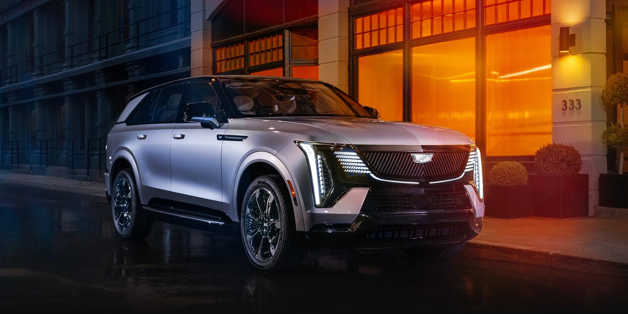 Le Cadillac Escalade IQ stationné dans la rue à côté d’un bâtiment la nuit.