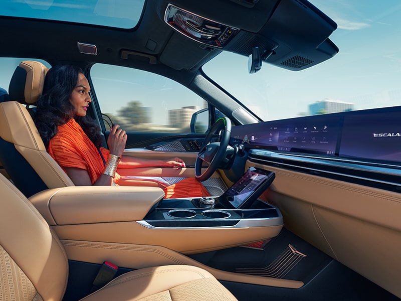 Une personne est assise sur le siège du conducteur du Cadillac Escalade IQ avec le sourire aux lèvres.