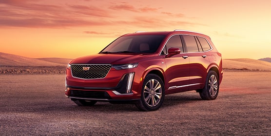 Front-side view of the 2025 Cadillac XT6 parked alone in the wilderness at sunset.