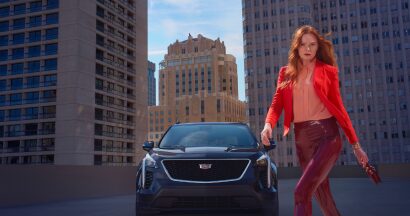 A person on a rooftop passing by a Cadillac vehicle for GM Discount Programs.