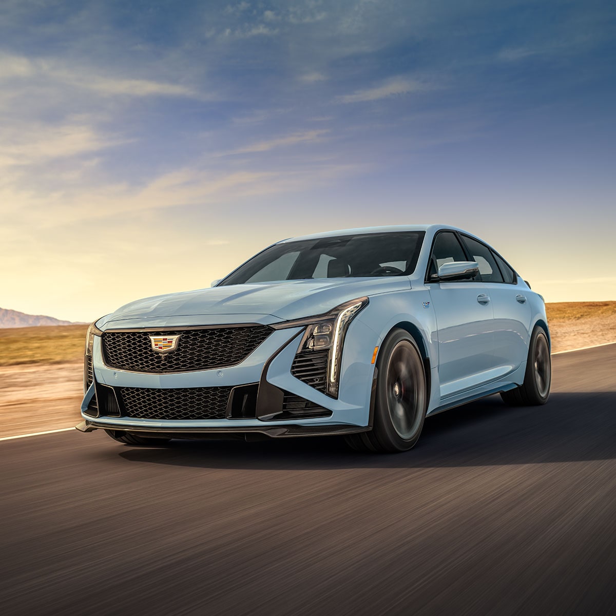 Vue latérale avant de la Cadillac CT5-V 2025 en mouvement sur une route aride.