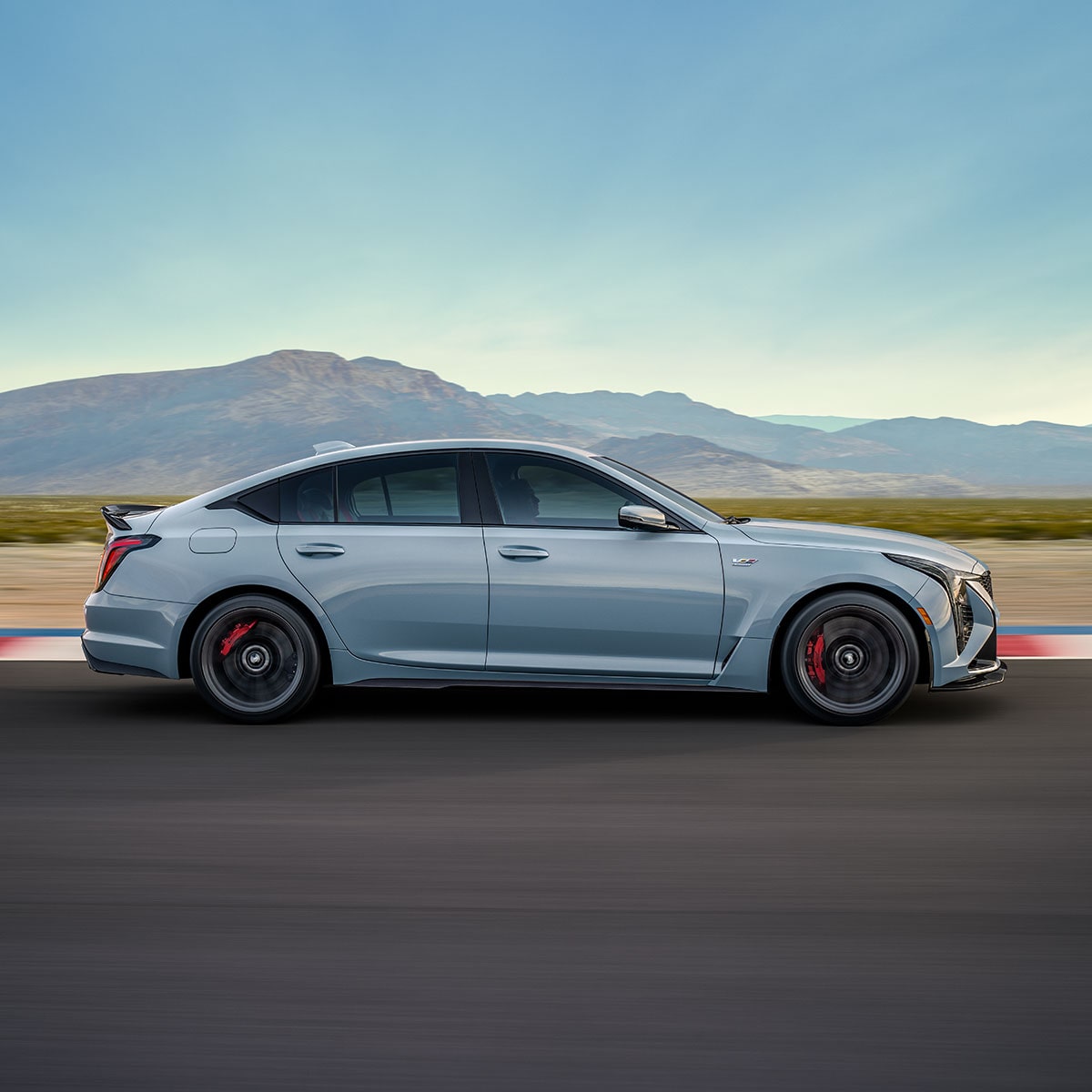 Vue latérale de la Cadillac CT5-V 2025 en mouvement sur une route de campagne.