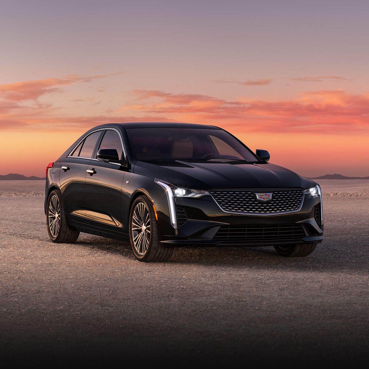 Berline de luxe Cadillac CT4 2026 stationnée seule sur un terrain rocailleux au coucher du soleil.