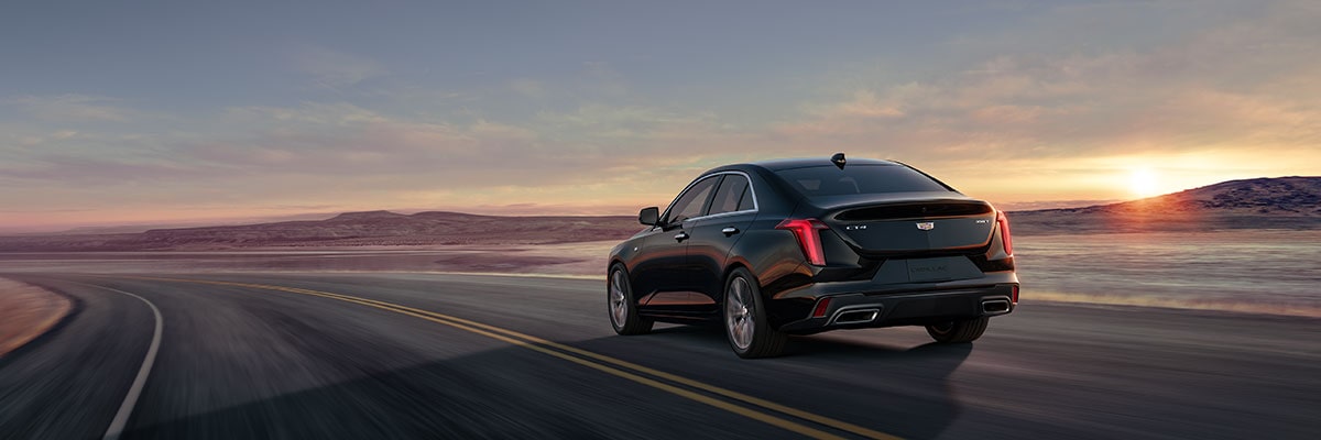 Back-side view of the 2026 Cadillac CT4 luxury sedan driving fast on the road.