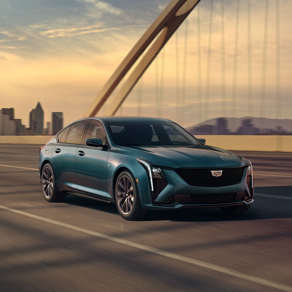 Front-side view of the 2026 Cadillac CT5 sedan driving on a bridge at sunset.