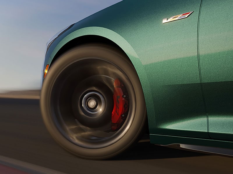 Gros plan flou des freins Brembo haute performance de la CT5-V, intégrés à la roue, en conduite sur route.