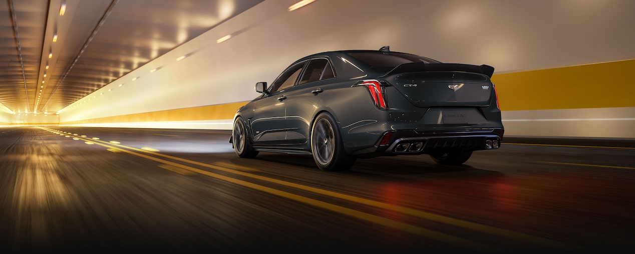 Vue arrière d'une Cadillac CT4-V Blackwing Sedan gris foncé traversant rapidement un tunnel fortement éclairé