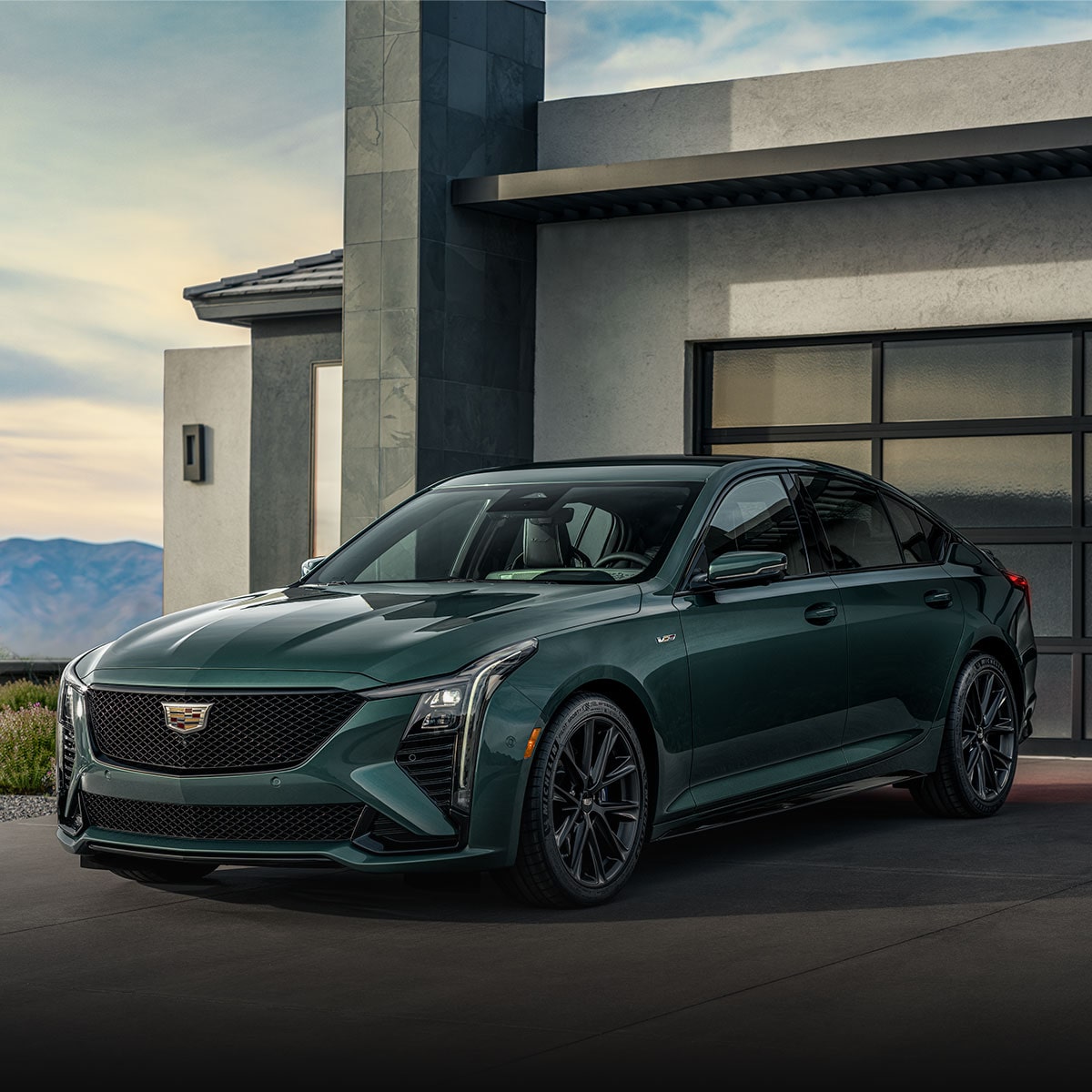 Front three-quarter view of a Cadillac CT5-V parked outside a modern home.