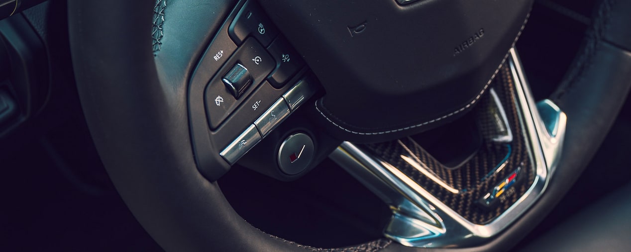 Close-up view of the steering wheel of a Cadillac V-series vehicle.
