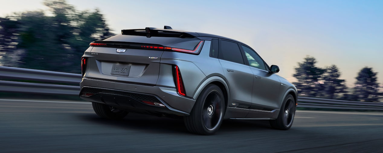 Rear-side view of a Cadillac LYRIQ-V driving alone on the road.