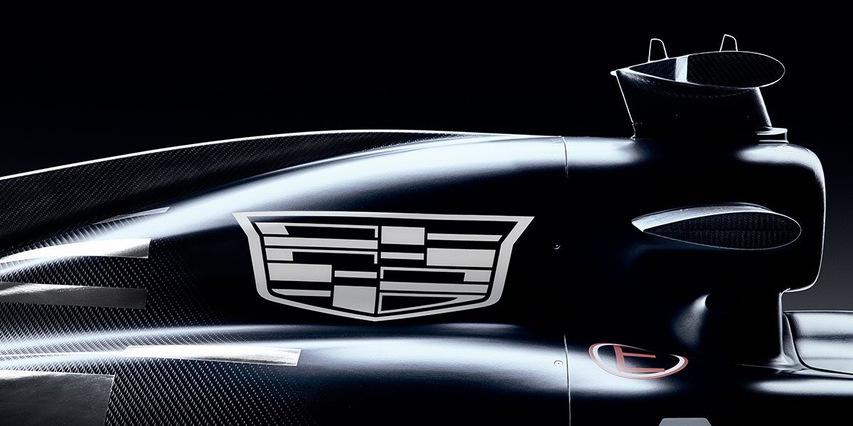 A Tight Angle Of the Cadillac Emblem Mounted On the Side Of a Black-And-White Formula Race Car With Reflections Highlighting the Contours Of the Bodywork.
