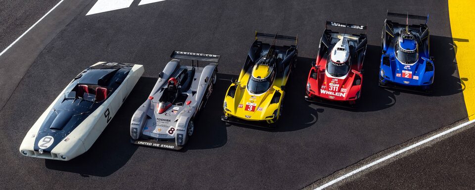 Five Cadillac racecars parked side by side on the race track.