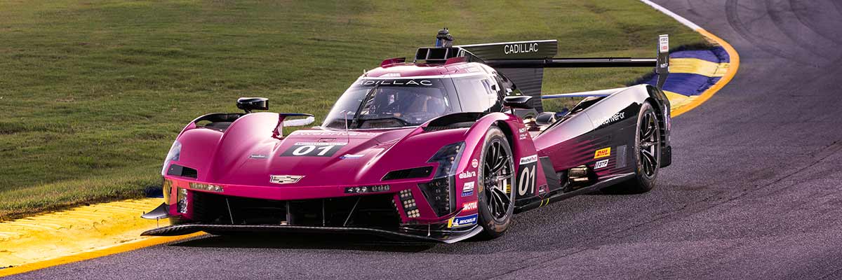 The Cadillac Racing V-Series.R as it races down the track at night.