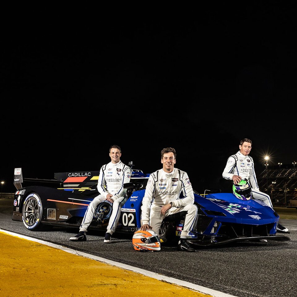 Trois coureurs automobiles à côté de la voiture de course électrifiée V-Series.R.