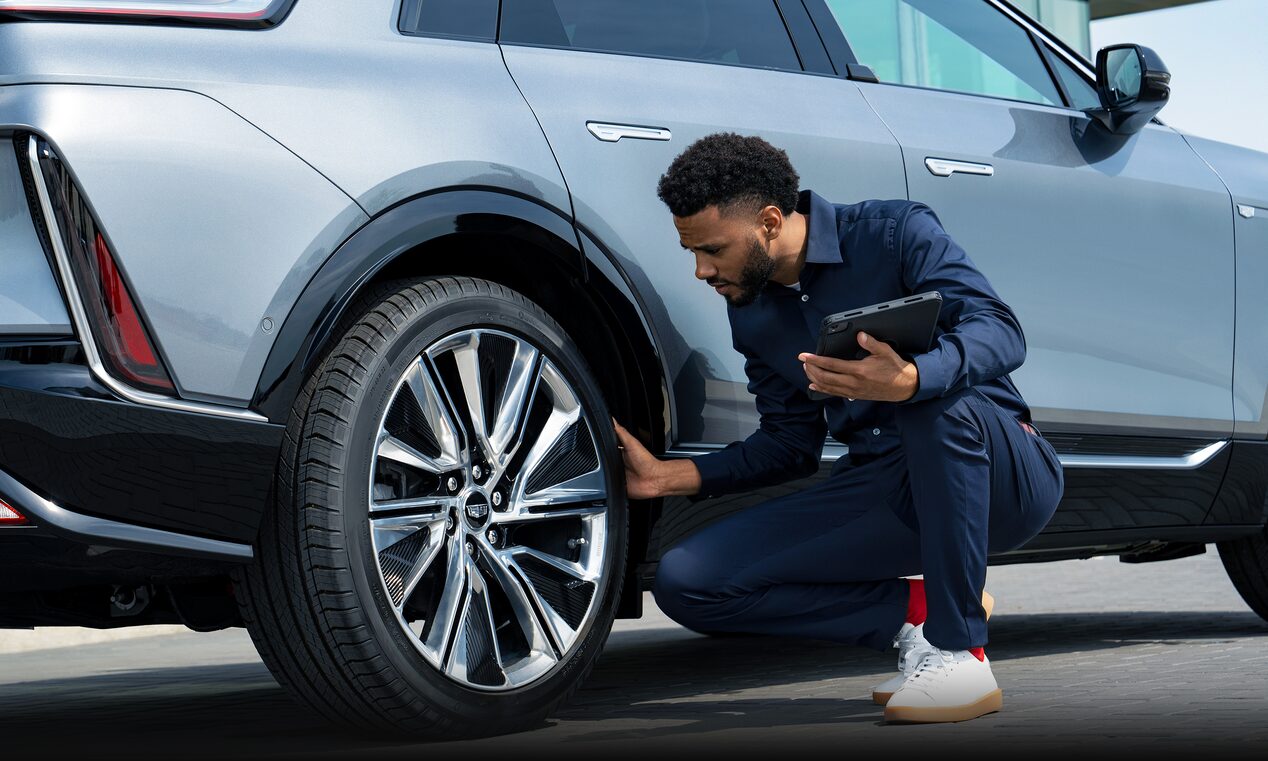 A Cadillac Service Representative Inspects a Tire for Damage