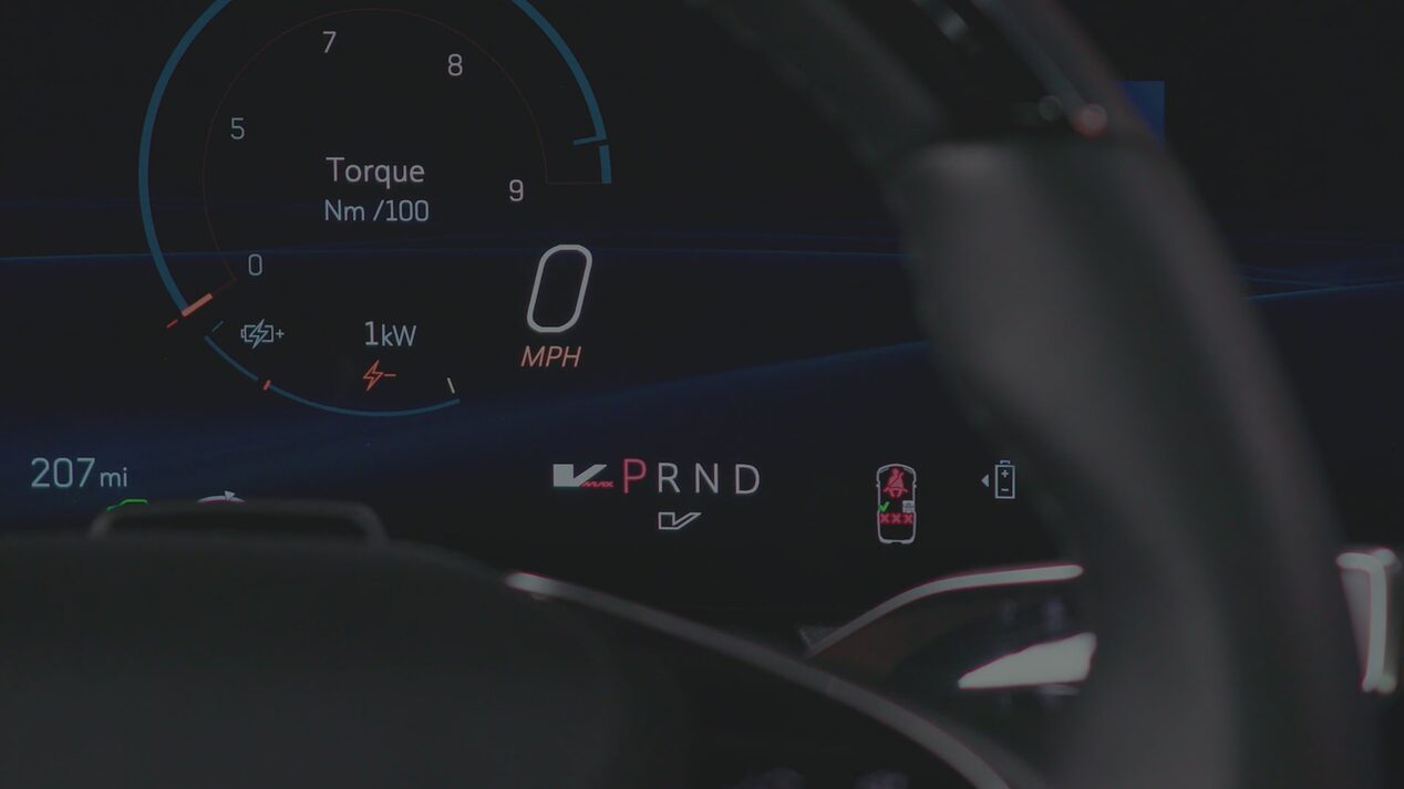 A Digital Cadillac OPTIQ Driver Display Showing Torque Output, Speed, And PRND Gear Indicators Partially Framed By the Steering Wheel.