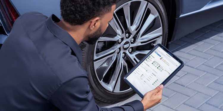Cadillac Certified Service Technician Inspecting Vehicle Information on a Tablet