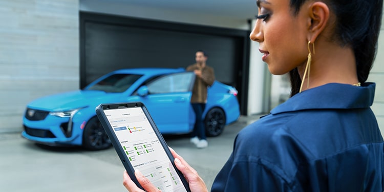 A Woman Inspecting a Tablet with Vehicle Information While a Man Stands by a Vehicle Nearby