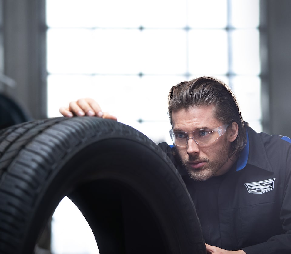 A Male Service Tech with Safety Glasses On Looking at the Tread of a Tire