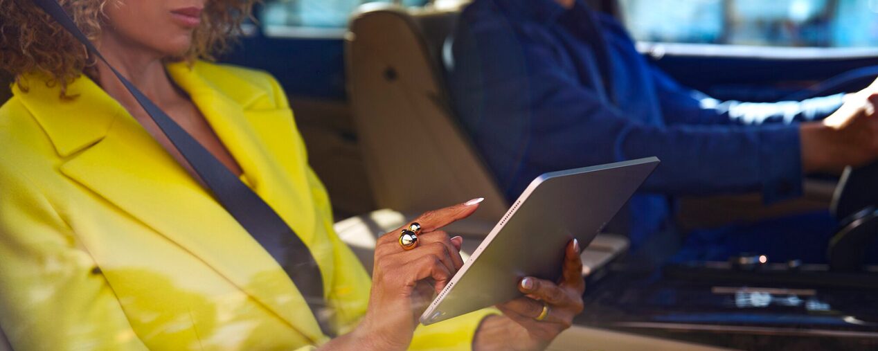 A Fashionably Dressed Woman in the Passenger Seat of a Cadillac Using an iPad