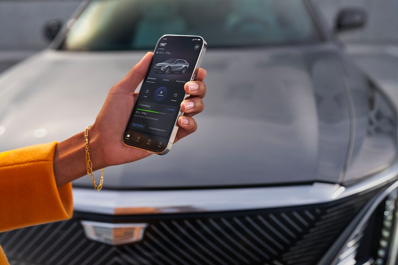 Close-up of a Woman Using the myCadillac App on Her Phone in Front of a LYRIQ
