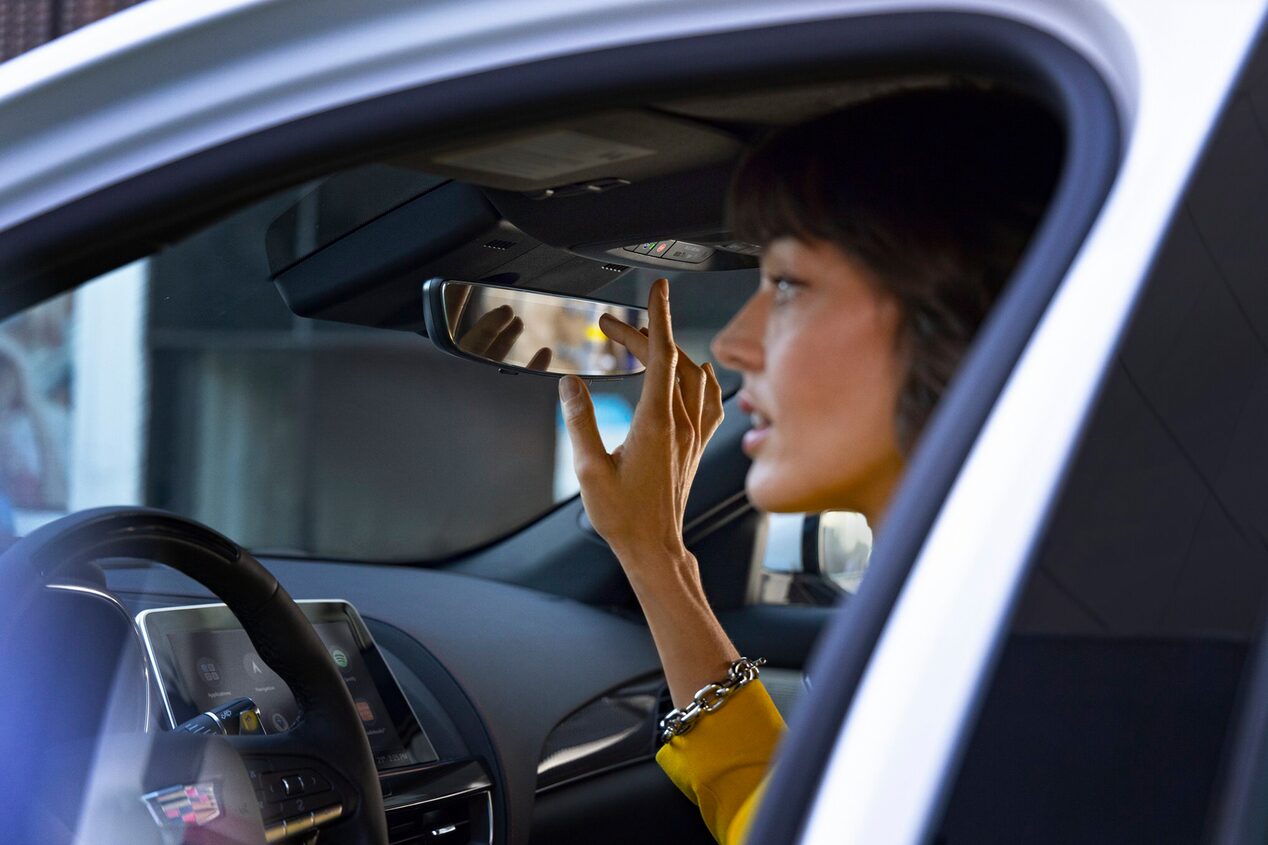 Close-Up of a Woman Pressing the OnStar Button Near the Rear View Mirror in a Cadillac