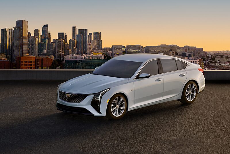 Three Quarters View of a White Cadillac Vehicle on a Rooftop with a City Skyline Seen in the Distance